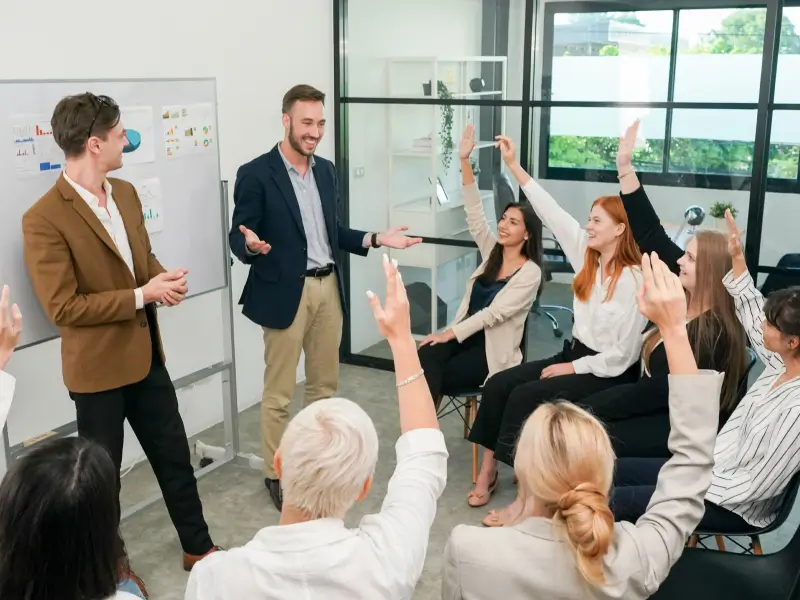 a group workshop session with students raising their hands